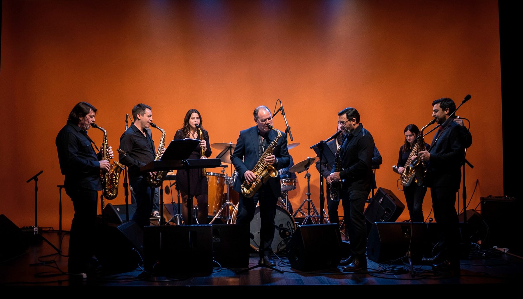 Jazz ensemble performing on a dimly lit stage, warm amber and deep blue tones, atmospheric concert mood