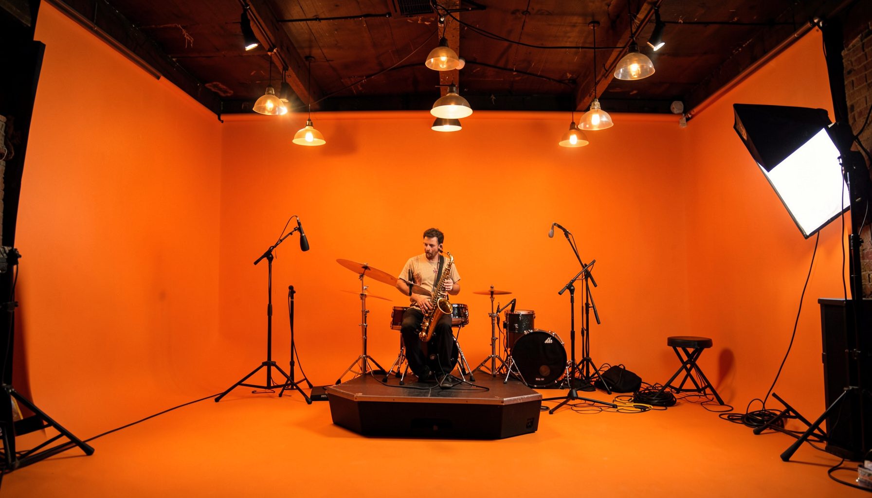 Cozy upstairs pub venue with low ceiling, warm pendant lights, and a small stage setup for acoustic jazz performances