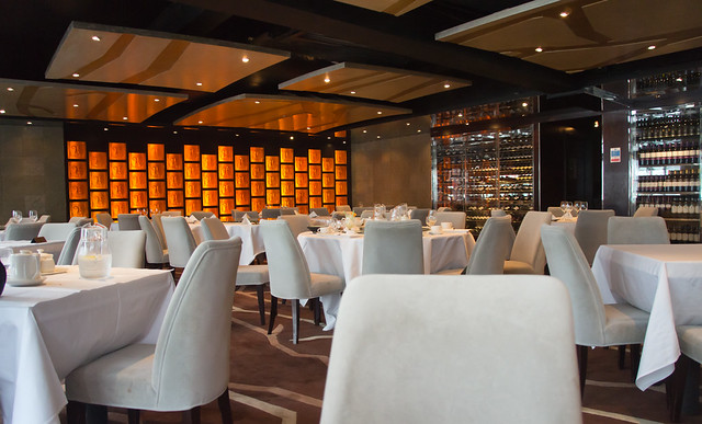 Elegant empty dining room with white tablecloths, beige chairs and warm lighting