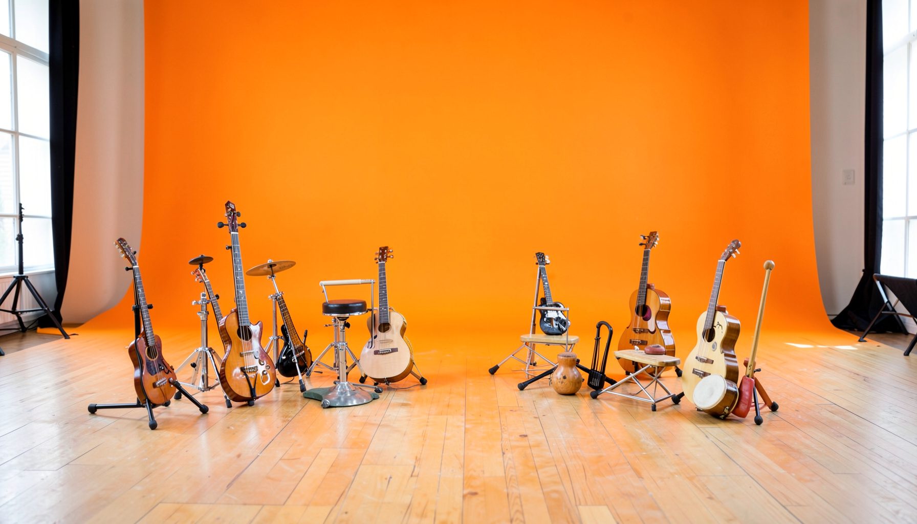 Bright community theatre space with wooden floor, natural light, and children's instruments arranged for a workshop setting