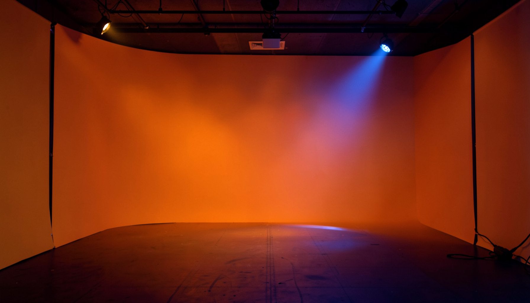 Warm stage lighting casting amber and deep blue hues across an empty jazz club interior, intimate and atmospheric