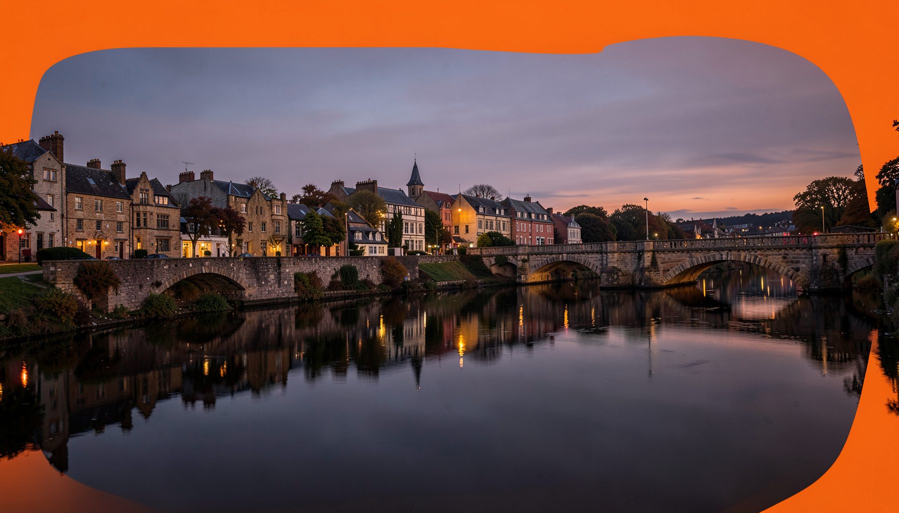 Warm evening view of Limerick city along the River Shannon, with stone bridges and historic buildings reflected in calm water under a dusky sky