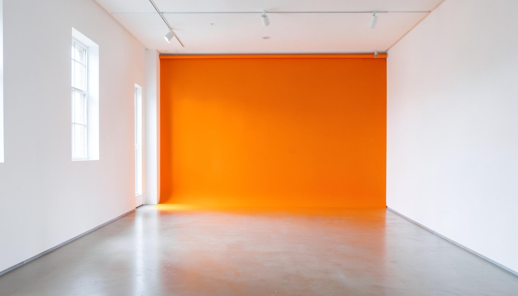 Bright gallery interior with white walls, polished floors, and natural daylight, serene cultural setting